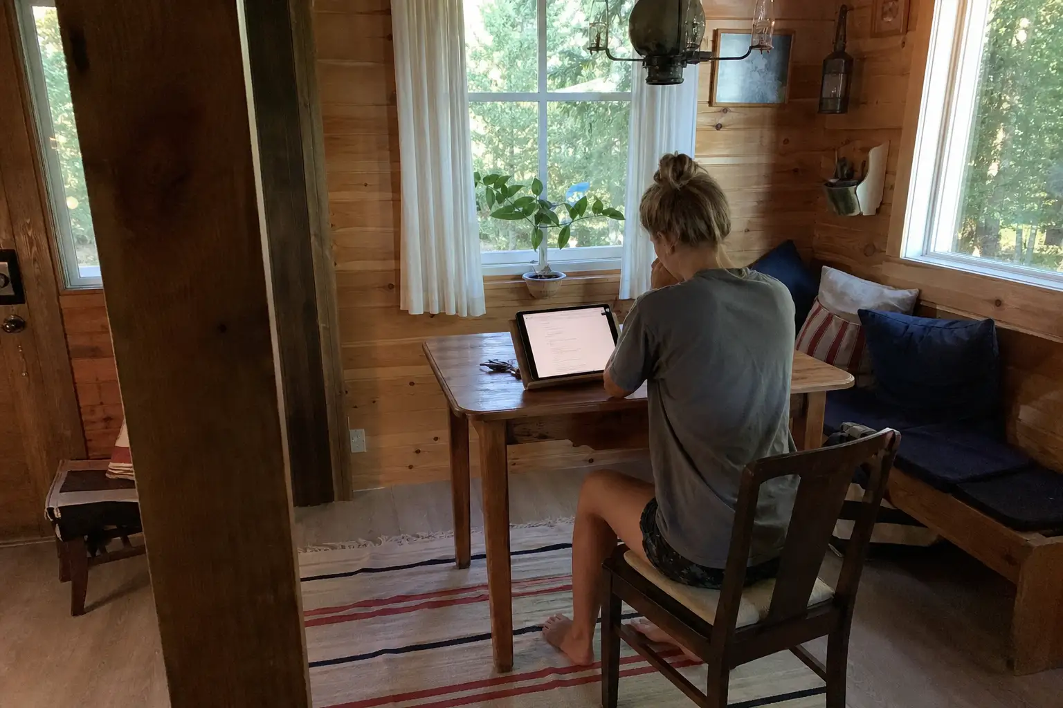 Person som sitter vid ett bord i en mysig stuga och planerar extra inkomst hemma via surfplatta.